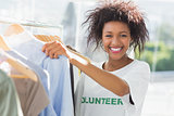 Smiling female volunteer by clothes rack