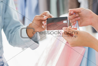Mid section of customer receiving shopping bags and credit card from saleswoman