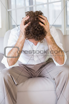 Well dressed man sitting with head in hands at home