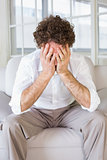 Well dressed man sitting with head in hands at home