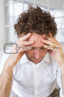 Well dressed man sitting with head in hands at home