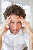 Worried man sitting with head in hands at home