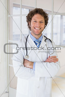 Happy male doctor with arms crossed in hospital