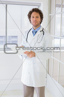 Serious male doctor with clipboard in hospital