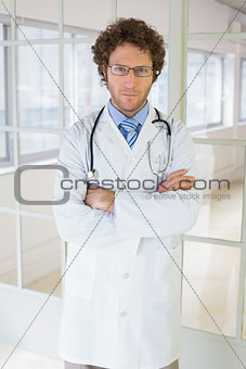 Serious male doctor standing with arms crossed in hospital