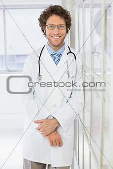 Happy handsome male doctor standing in hospital