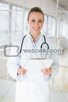 Happy beautiful female doctor with clipboard in hospital