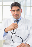 Serious male doctor holding stethoscope