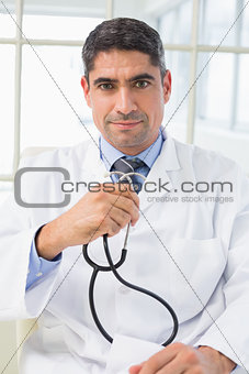 Serious male doctor holding stethoscope