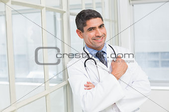 Smiling male doctor with arms crossed in hospital