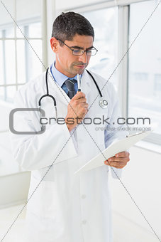 Male doctor reading reports in hospital