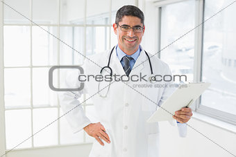 Smiling male doctor holding reports in hospital