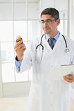 Male doctor looking at a bottle of pills