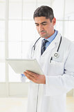 Serious male doctor using digital tablet