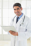 Smiling male doctor using digital tablet