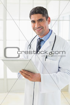 Smiling male doctor using digital tablet