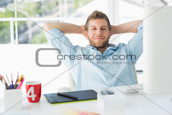 Designer relaxing at his desk smiling at camera