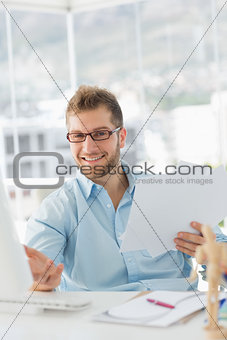 Handsome designer sitting at his desk gesturing at camera