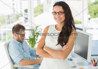 Pretty designer smiling at camera leaning on desk