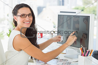 Pretty young editor working at her desk smiling at camera