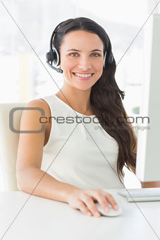 Smiling call centre agent sitting at her desk