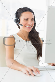 Smiling call centre agent sitting at her desk on a call