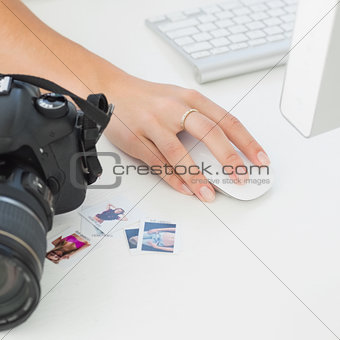 Digital camera on photographers desk with womans hand on mouse
