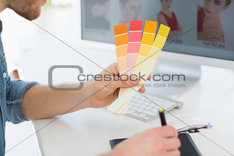 Designer working with digitizer holding colour chart at his desk
