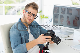 Handsome photographer holding his camera smiling at camera