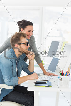 Team of smiling designers looking at the computer