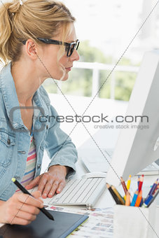 Blonde focused designer using digitizer at her desk