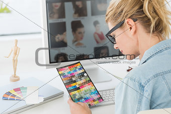 Blonde designer looking at colour chart at her desk