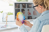 Blonde focused designer working at her desk holding a colour wheel