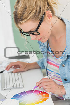 Blonde designer working at her desk using a colour wheel