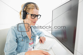 Blonde designer wearing headphones working at computer