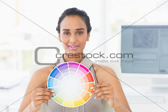 Designer at her desk showing colour wheel to camera