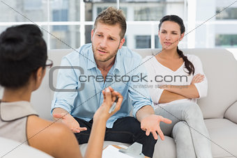 Unhappy couple at therapy session with man talking to therapist