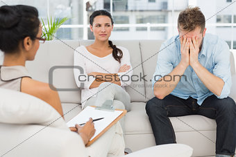 Unhappy couple sitting on sofa at therapy session