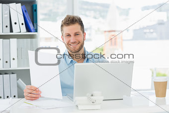 Handsome man working at his desk on laptop smiling at camera