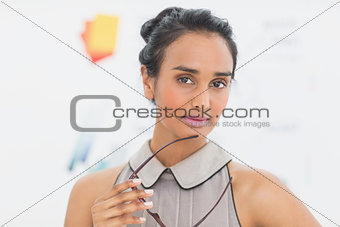 Serious designer looking at camera holding her glasses