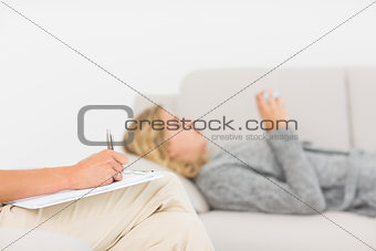 Therapist taking notes on her patient on the sofa