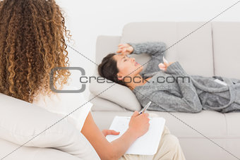 Therapist writing notes on her crying patient on the couch