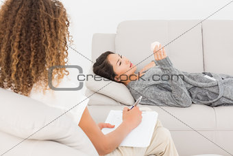 Therapist writing notes on her upset patient on the couch