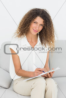 Smiling therapist looking at camera taking notes
