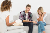 Man speaking to therapist at couples therapy while woman is crying