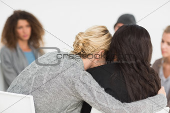 Women embracing in rehab group at therapy