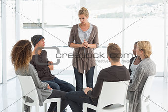 Rehab group listening to woman standing up introducing herself