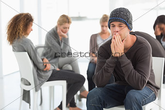 Upset man at rehab group with hands to face