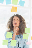 Thinking pretty designer looking at sticky notes on window