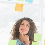Thinking smiling designer looking at sticky notes on window